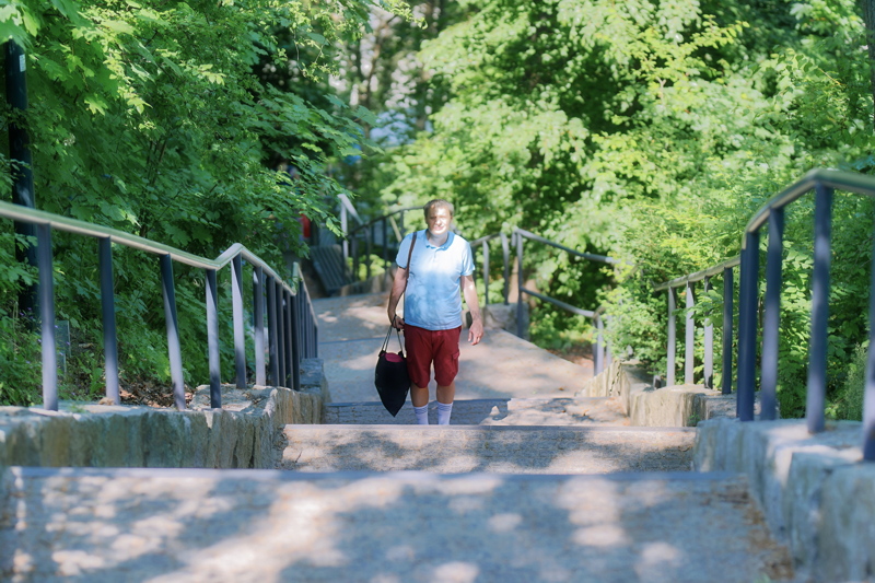 15 - A person walking up a long, outdoor stone staircase in a park setting